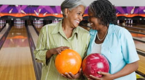 Two women smiling with bowling balls